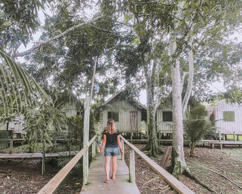 Woman standing by plants against trees