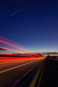 Light trails on road against clear sky at night