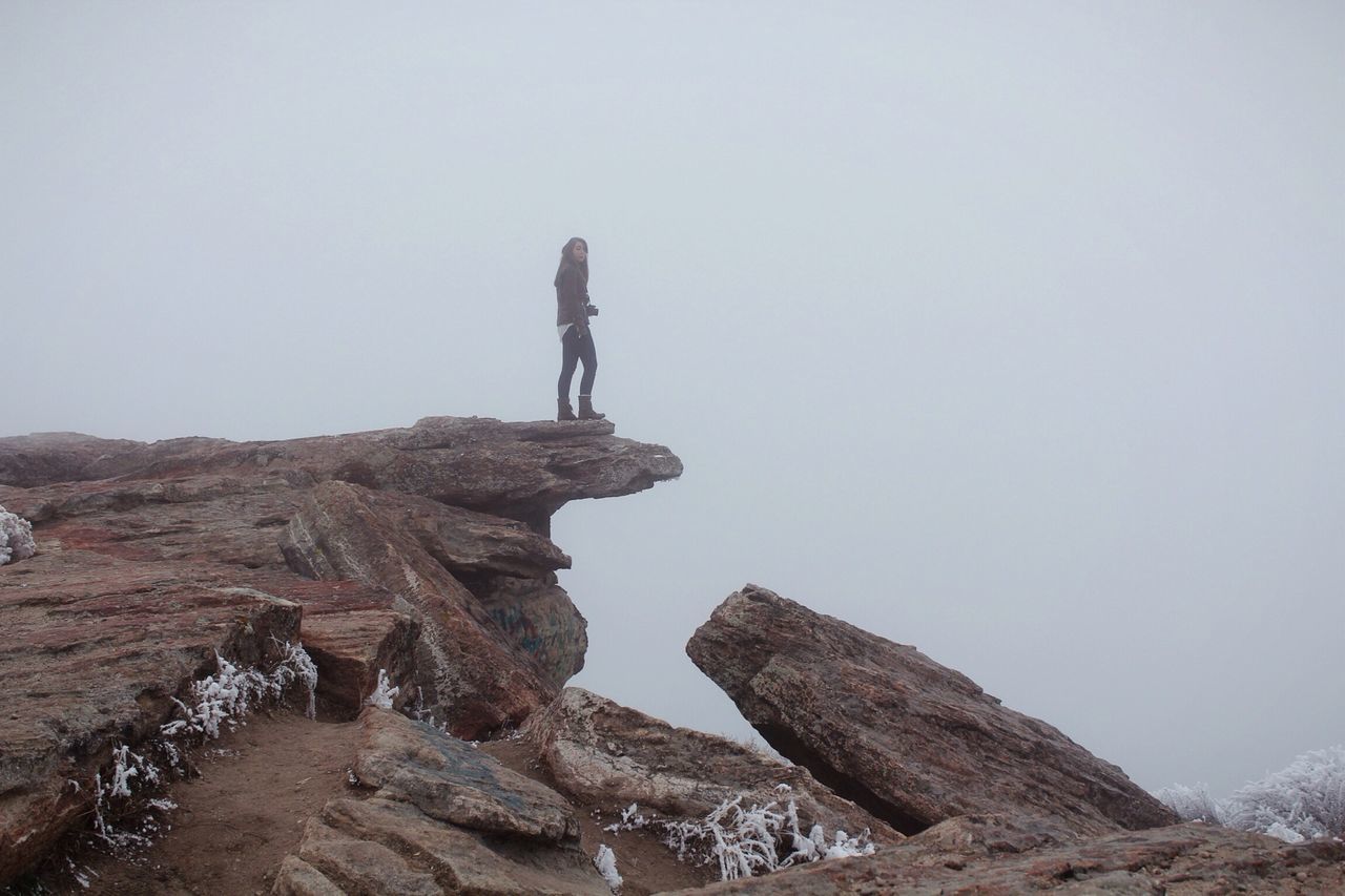 lifestyles, leisure activity, men, rock - object, full length, mountain, rock formation, clear sky, adventure, standing, low angle view, copy space, hiking, tranquility, rock, cliff, tourist, tranquil scene