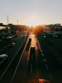 Cars on road in city against sky during sunset