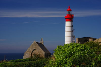 Lighthouse by building against sky