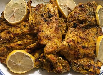 Close-up of roasted chicken with lemons sliced in plate