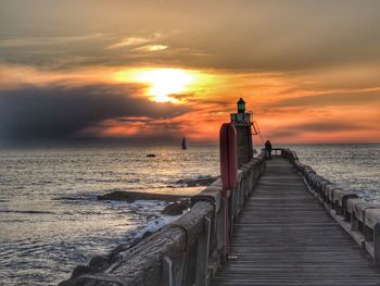 Pier on sea against sky during sunset