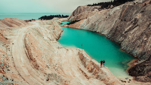 High angle view of hikers standing on cliff by river