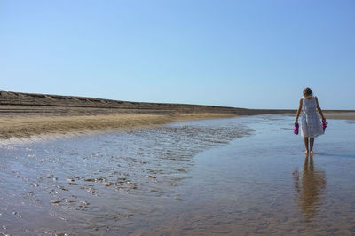 View of woman walking on beach against clear sky