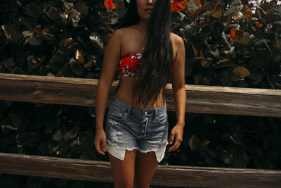 Midsection of woman standing against wooden wall