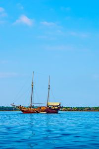 Sailboat in sea against blue sky