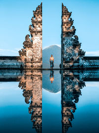 Reflection of man in water against blue sky