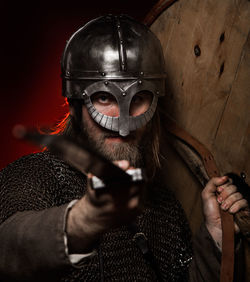 Portrait of viking wearing helmet while holding sword and shield 