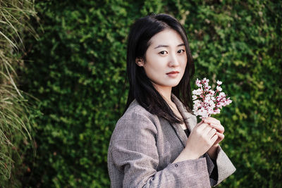 Beautiful chinese asian woman holding almond tree flowers.spring. selective focus on flowers