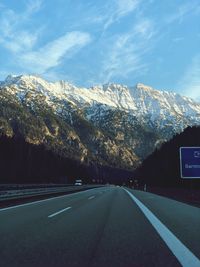Road by mountains against sky