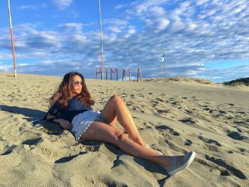 Full length of woman lying on beach against sky