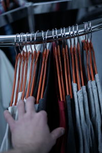 Cropped hand of woman holding clothes in shop