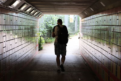 Full length rear view of man walking in underground walkway