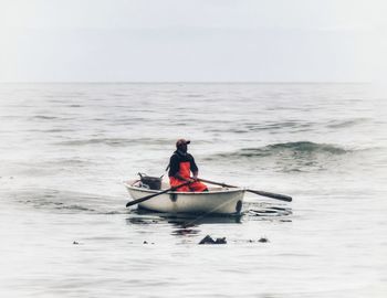 Man in boat on sea against sky