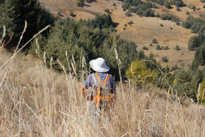 Rear view of woman standing on field during sunny day