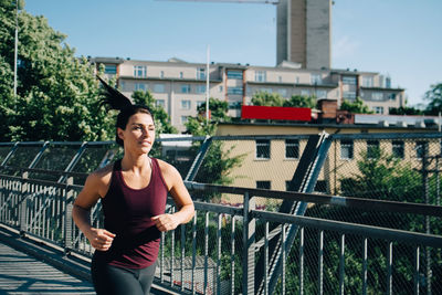Confident female athlete jogging on bridge in city