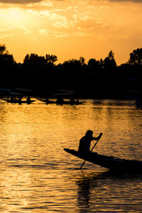 Silhouette man on boat against sky during sunset