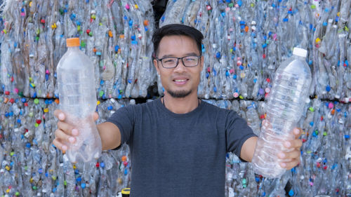 Portrait of smiling man standing by bottles