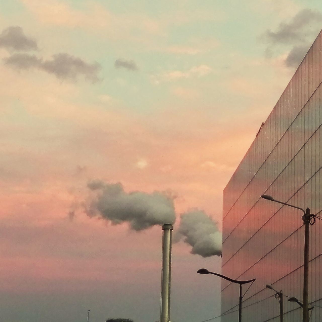 LOW ANGLE VIEW OF SMOKE STACKS AGAINST SKY DURING SUNSET