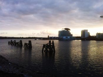 View of cityscape at sea against cloudy sky