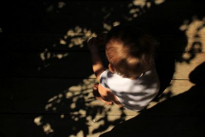 High angle view of boy crouching on boardwalk