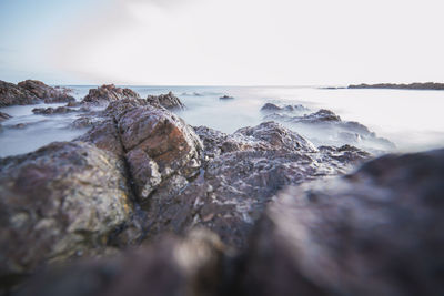 Close-up of rocks in sea against sky