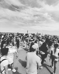 Rear view of people on street in city against sky