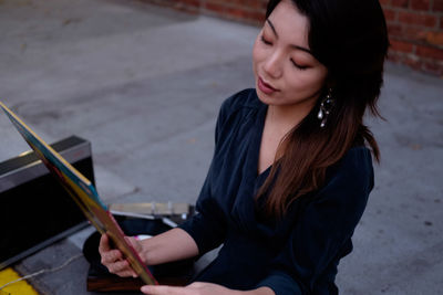 Young woman looking down while sitting outdoors