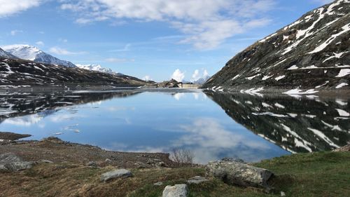 Scenic view of lake by snowcapped mountains against sky