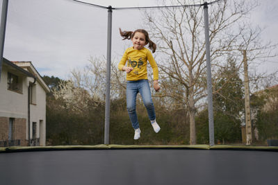 Girl jumping on trampoline in yard