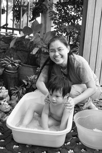 Portrait of happy mother bathing son at yard