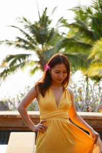Beautiful woman in yellow dress against palm trees