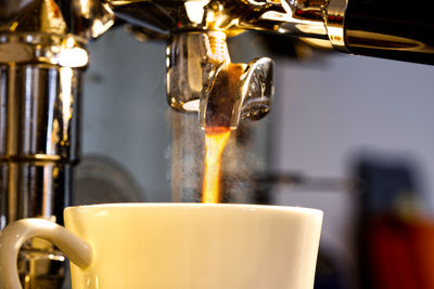 Close-up of coffee cup and coffee running out of espresso machine