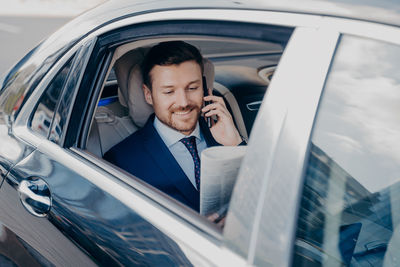 Young man using mobile phone in mirror