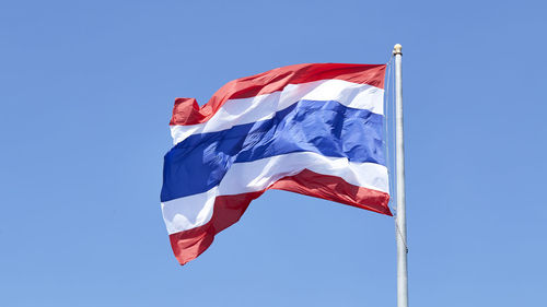 Low angle view of flag against blue sky