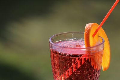 Close-up of red drink served with orange slice