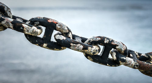 Close-up of rusty chain against sky