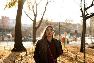 Portrait of young woman standing against trees