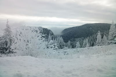 Scenic view of snow covered mountains against cloudy sky