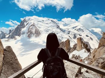 Rear view of woman walking on snowcapped mountains against sky