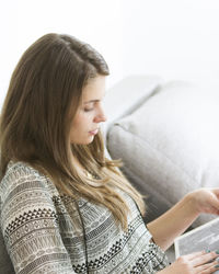 Close-up of young woman reading book while sitting at home