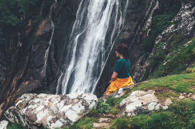 Rear view of man looking at waterfall