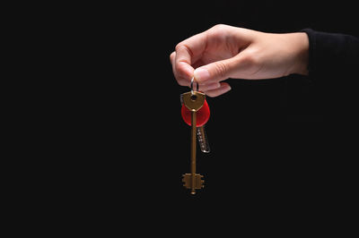 Close-up of hand holding trophy against black background