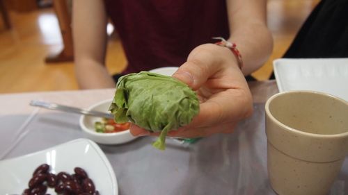 Midsection of woman holding food while sitting on table at restaurant