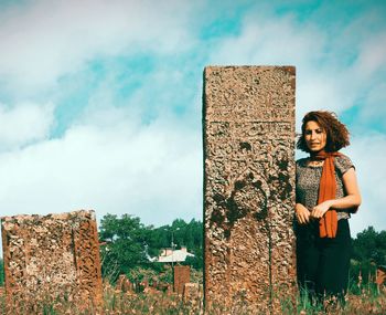 Young woman looking away while standing against sky