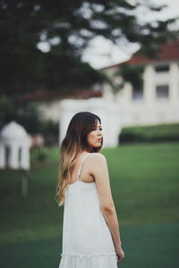 Young woman looking away while standing outdoors