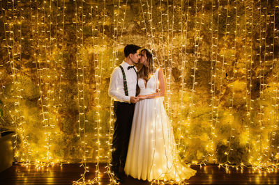 Full length of couple embracing against illuminated lighting