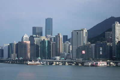 Sea and buildings against in city against sky