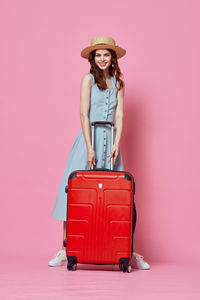 Portrait of young woman standing against red background